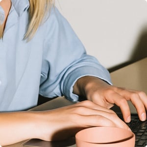Rounded-woman-typing-with-pink-cup